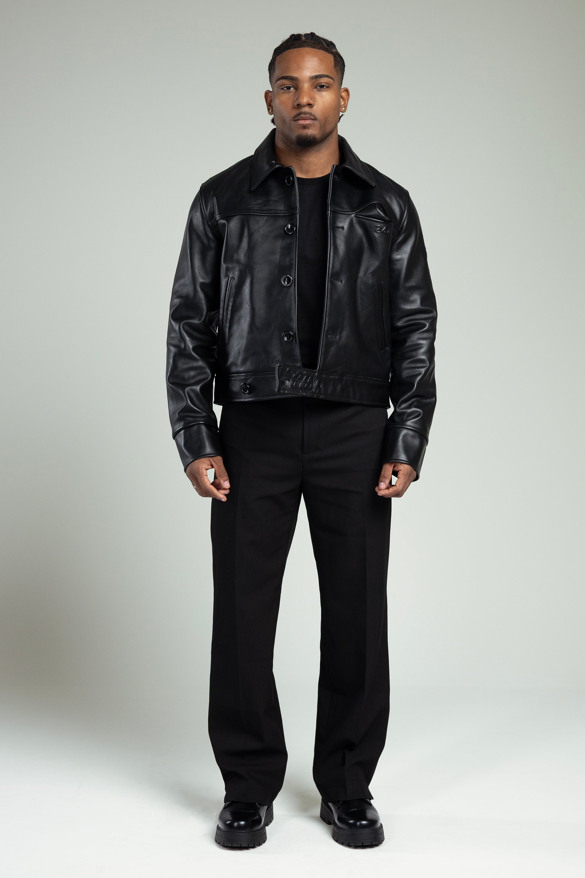 Man wearing a the 244 angels at heart black cowhide leather jacket and pants on a grey background. Full body shot